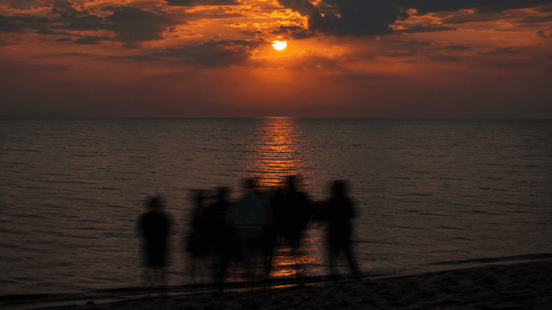 Friends gathered on a beach at sunset
